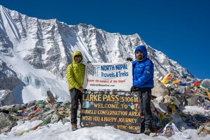 Trekker happy to click photo at larkya la pass during Manaslu Circuit Trek holding banner of North Nepal Trek.